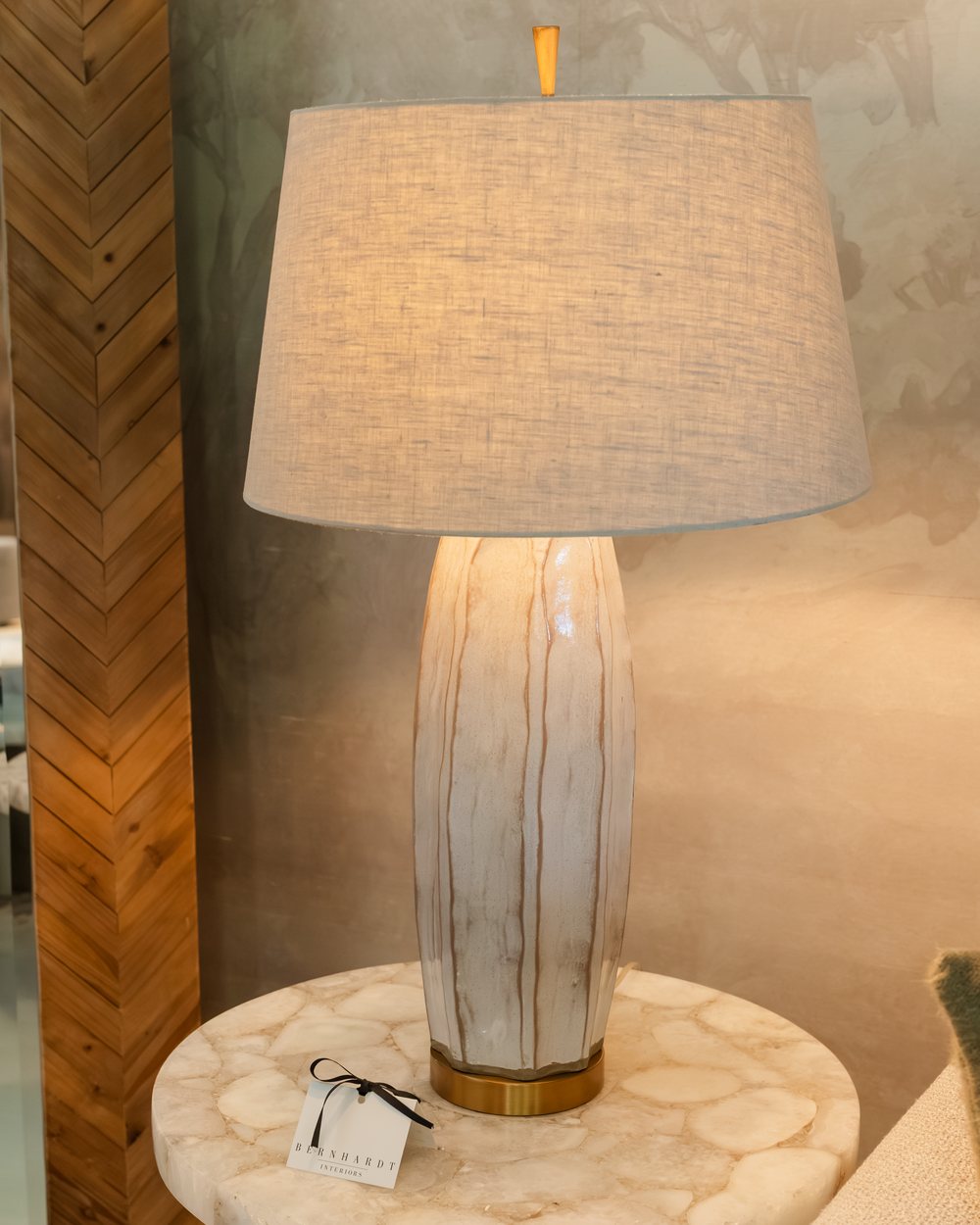 A carved driftwood lamp on an onyx table against a herringbone wall