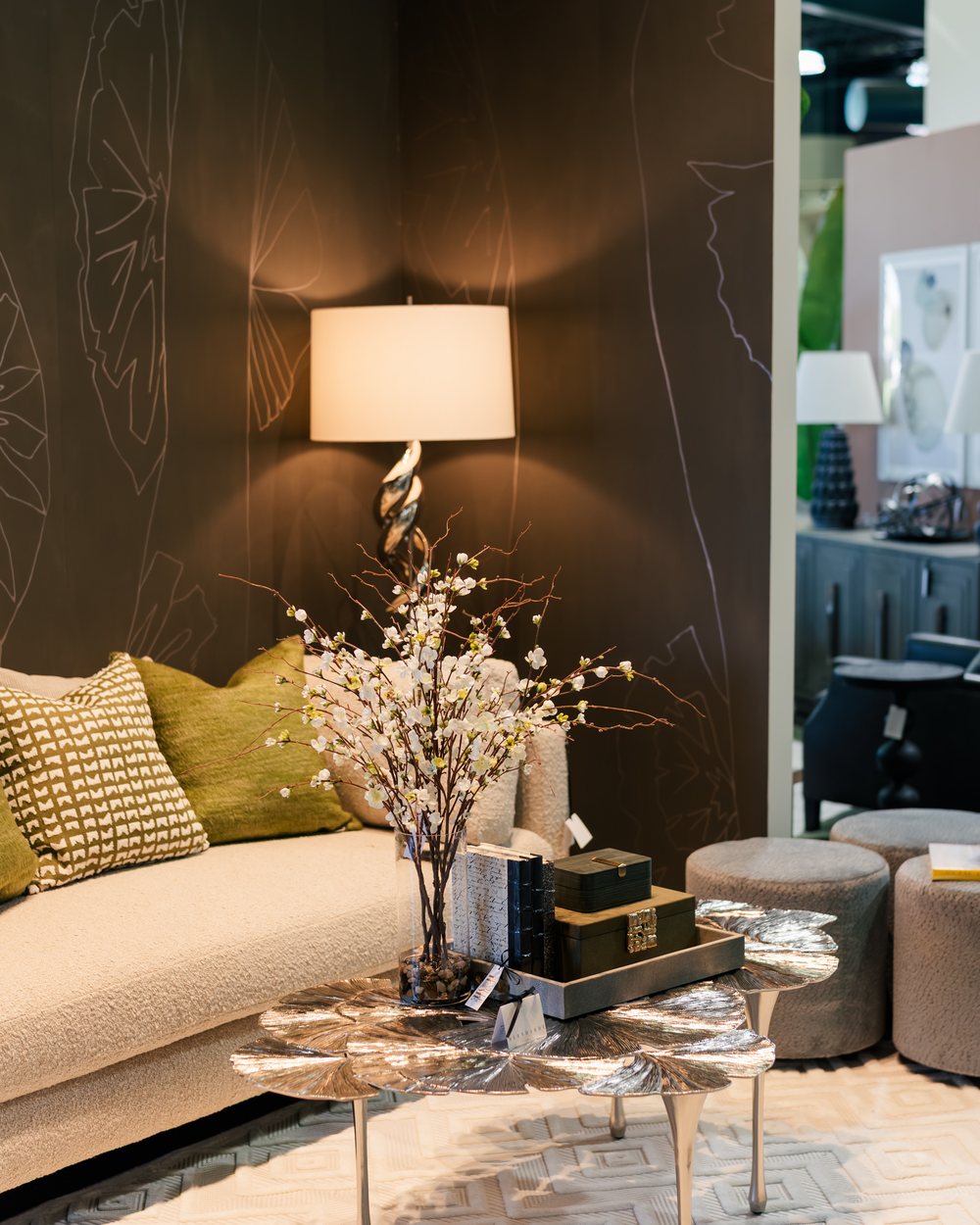 A cream Bernhardt sofa with olive pillows and a berry-branch arrangement against the hand-drawn ginkgo wall