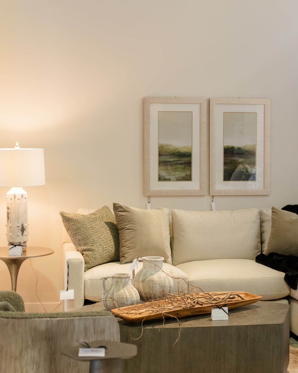Cream seating and swivel chairs around a cerused-oak table beneath framed coastal art