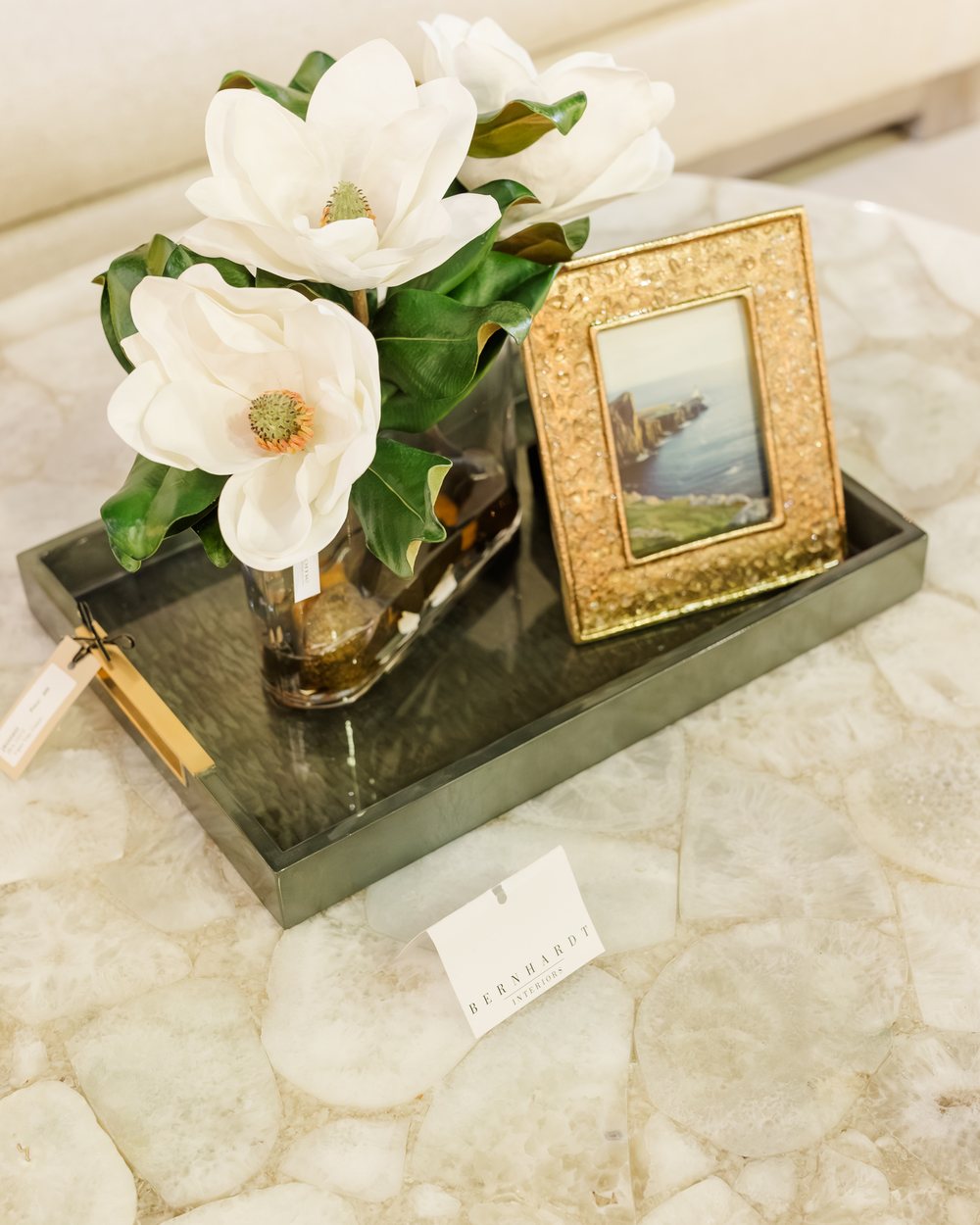 A white magnolia and a gilt-framed landscape styled on an agate tray