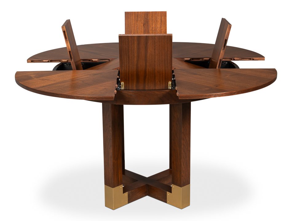 A round walnut jupe table halfway open: its four quarters have slid apart and four leaves stand upright as they swing up from beneath the top.