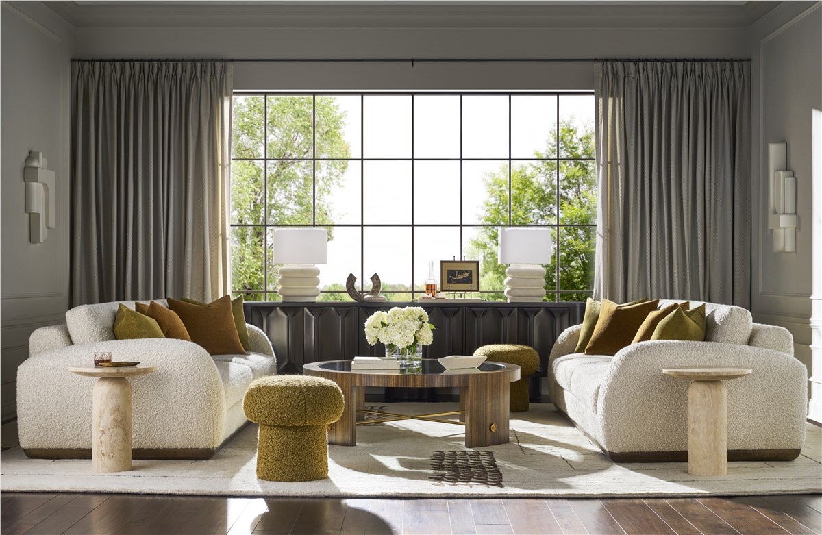 A Vanguard living room arranged for conversation: two boucle sofas facing each other across a cocktail table, every front leg on the rug, a long credenza and window wall behind.